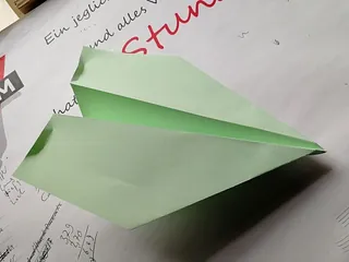 Grünes Papierflugzeug.